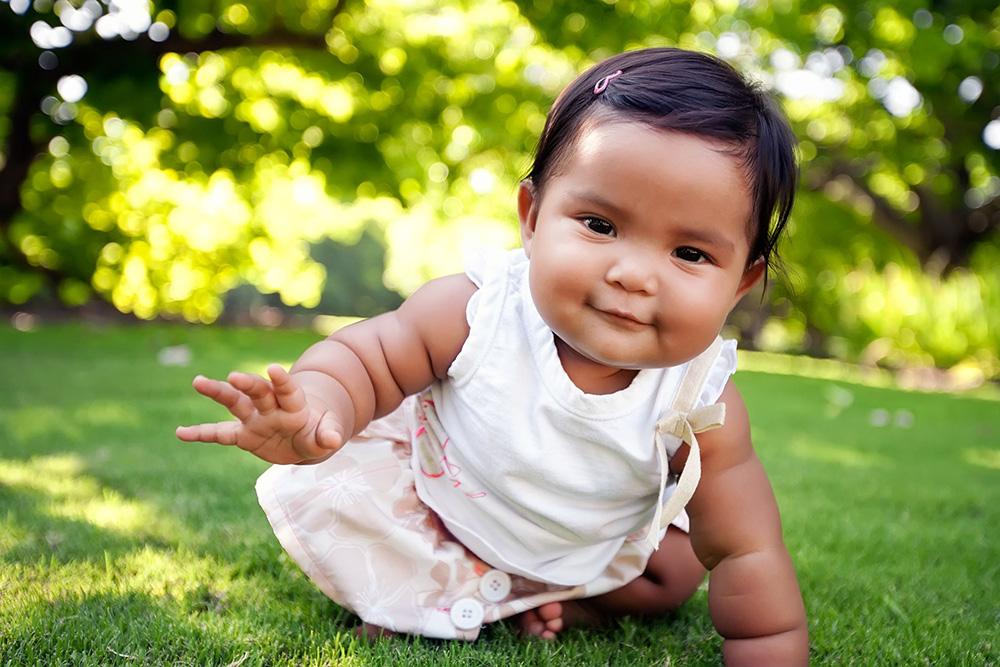 Cute-baby-girl-with-a-smile-on-her-face,-reaching-out-to-take-her-first-crawling-step
